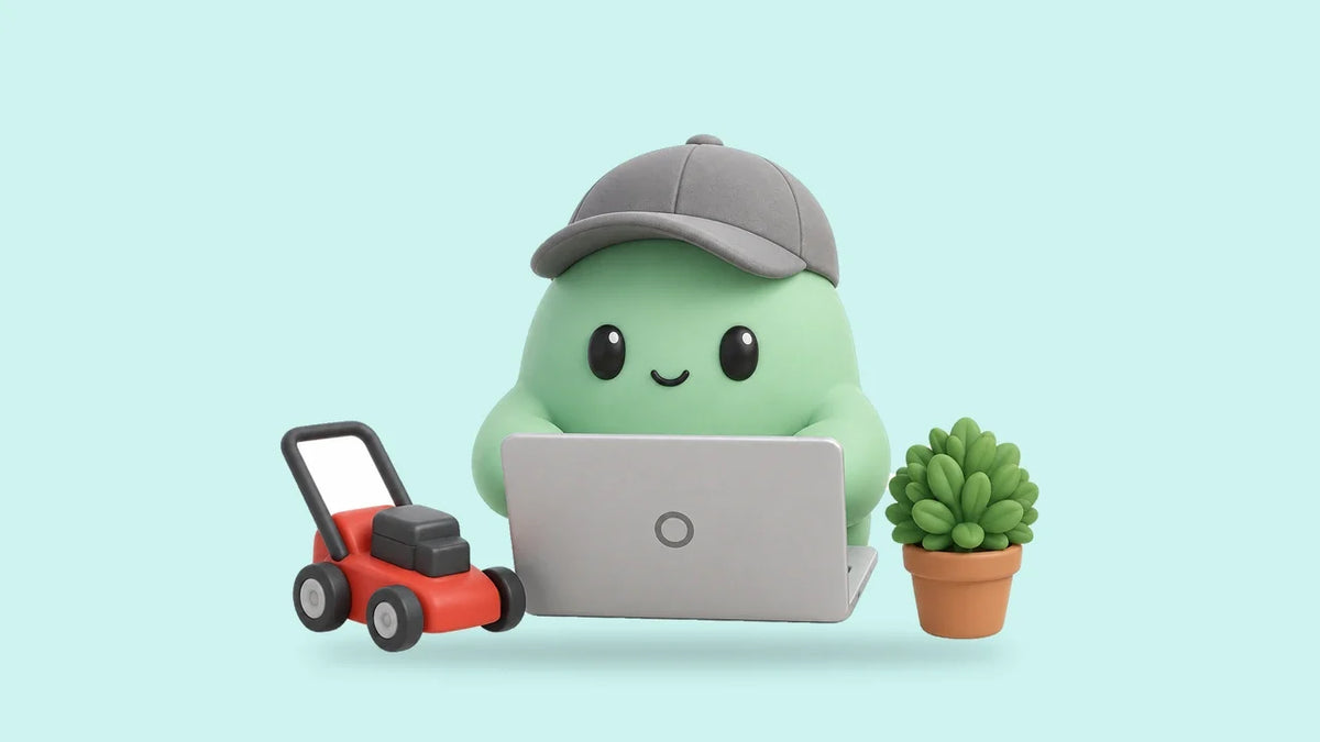 Hank at a laptop beside a small toy lawn mower and a potted shrub