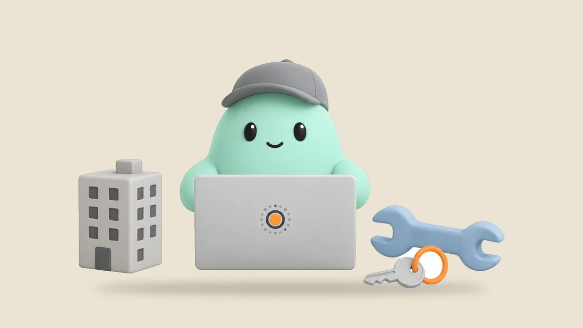 Hank at a laptop beside a small apartment building model, a wrench and a key on a ring