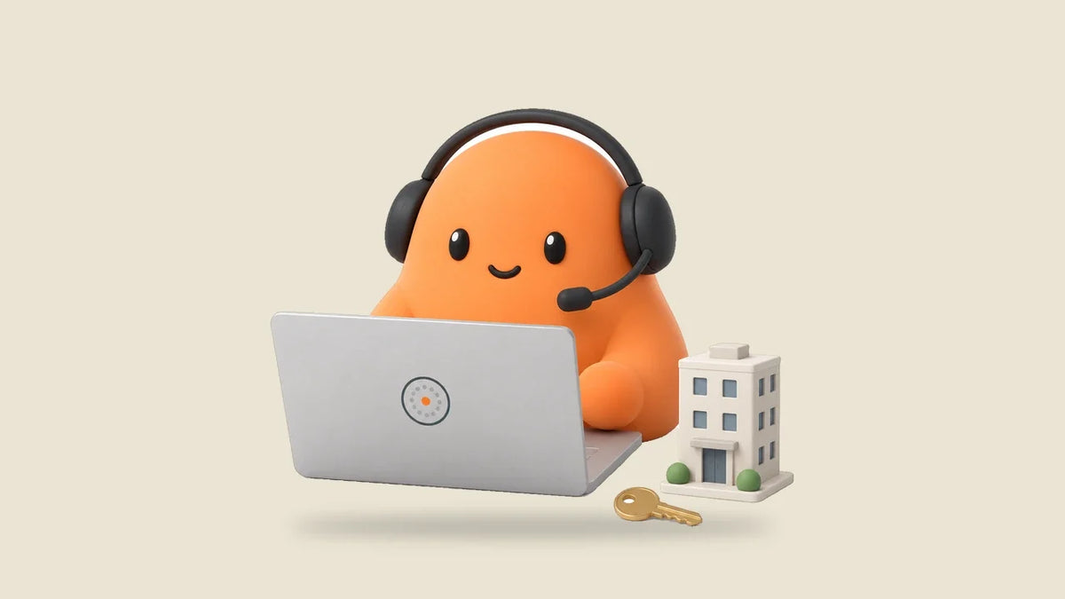 Mia at a laptop beside a small toy apartment building and a key