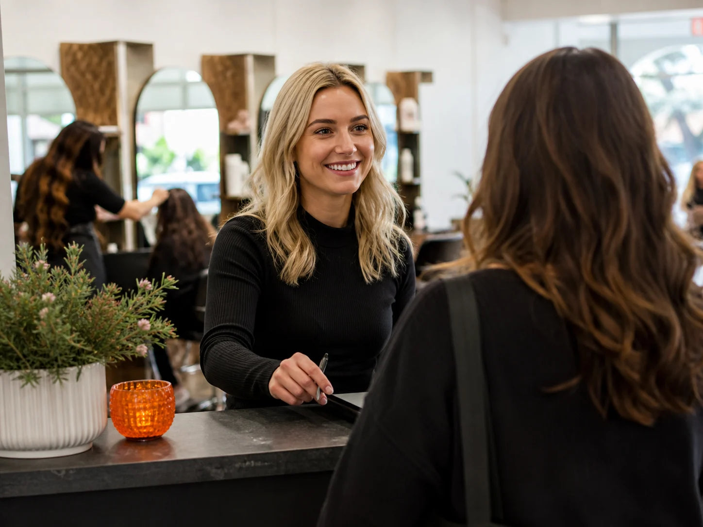 Salon receptionist welcoming a client and coordinating an appointment